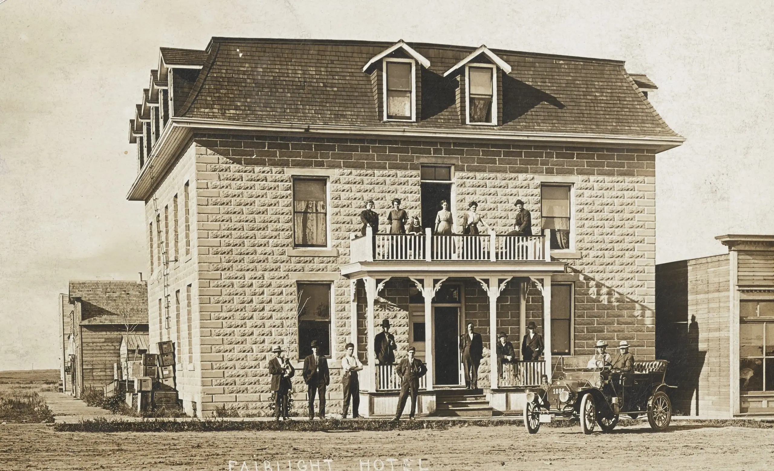 Fairlight Hotel with people on the balcony and an early car